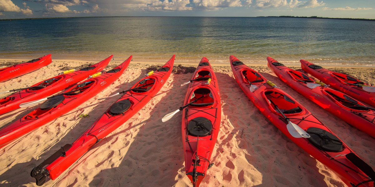 A row of red sea kayaks lined up on a beach at the Bay of Pigs in Cuba.