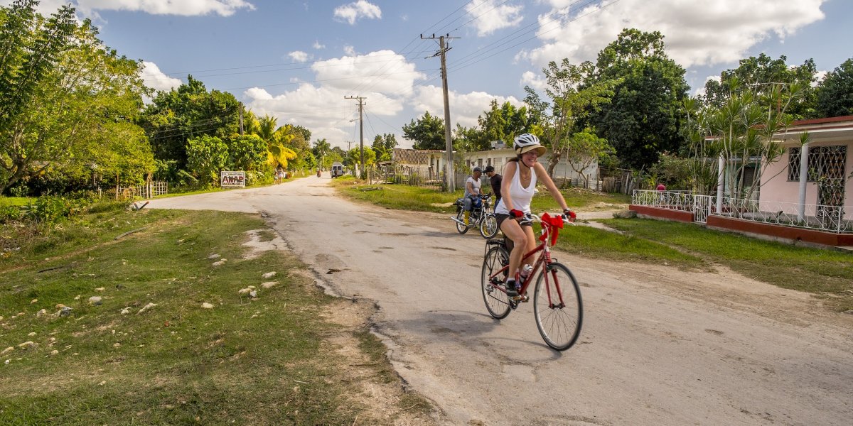 Traveler cycling through a rural Cuban village, enjoying cultural immersion and scenic routes on guided Cuba trips.