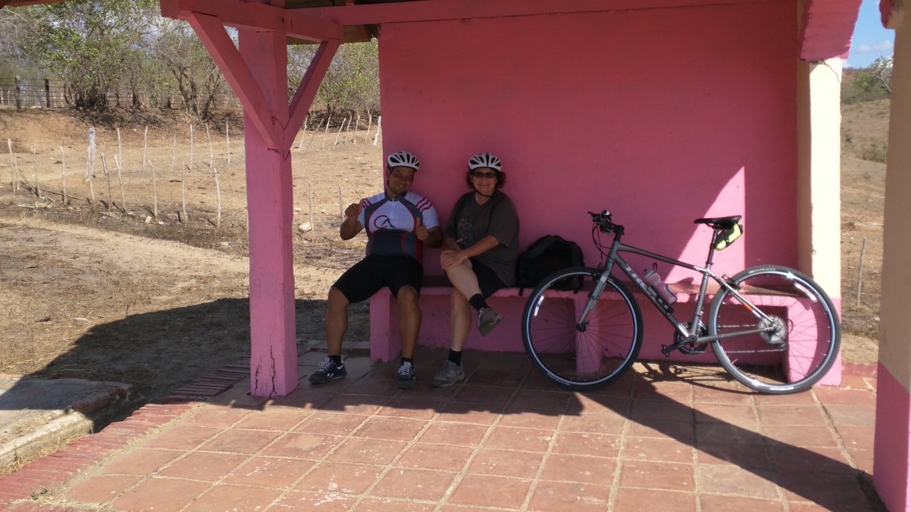Two tourists and a bike sitting at a pink rest stop