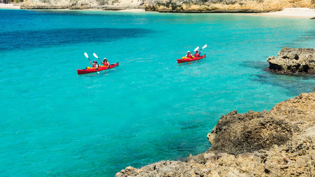Two red sea kayaks atop crystal clear turquoise water in the Caribbean