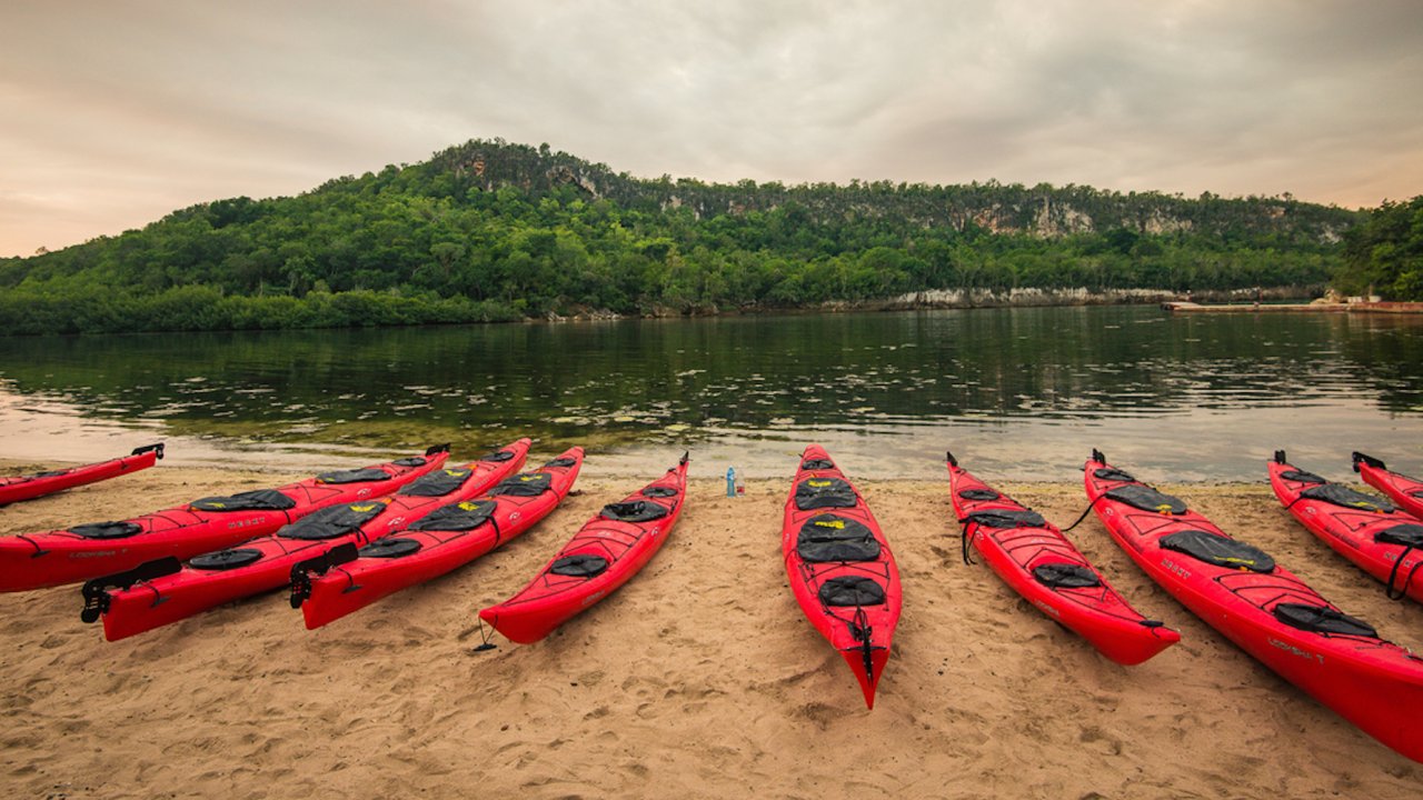 A row of red kayaks lined up on the beach in Cuba