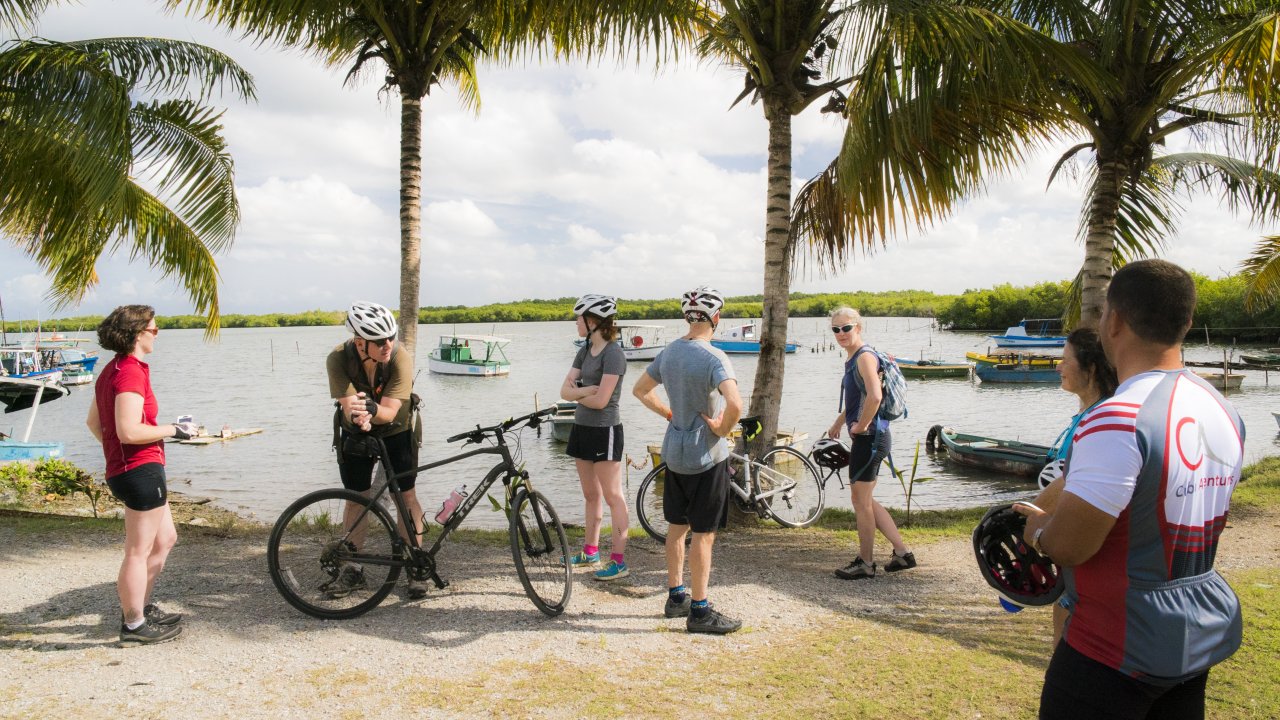A group of bikers standing next to their bike on the beach in Cuba