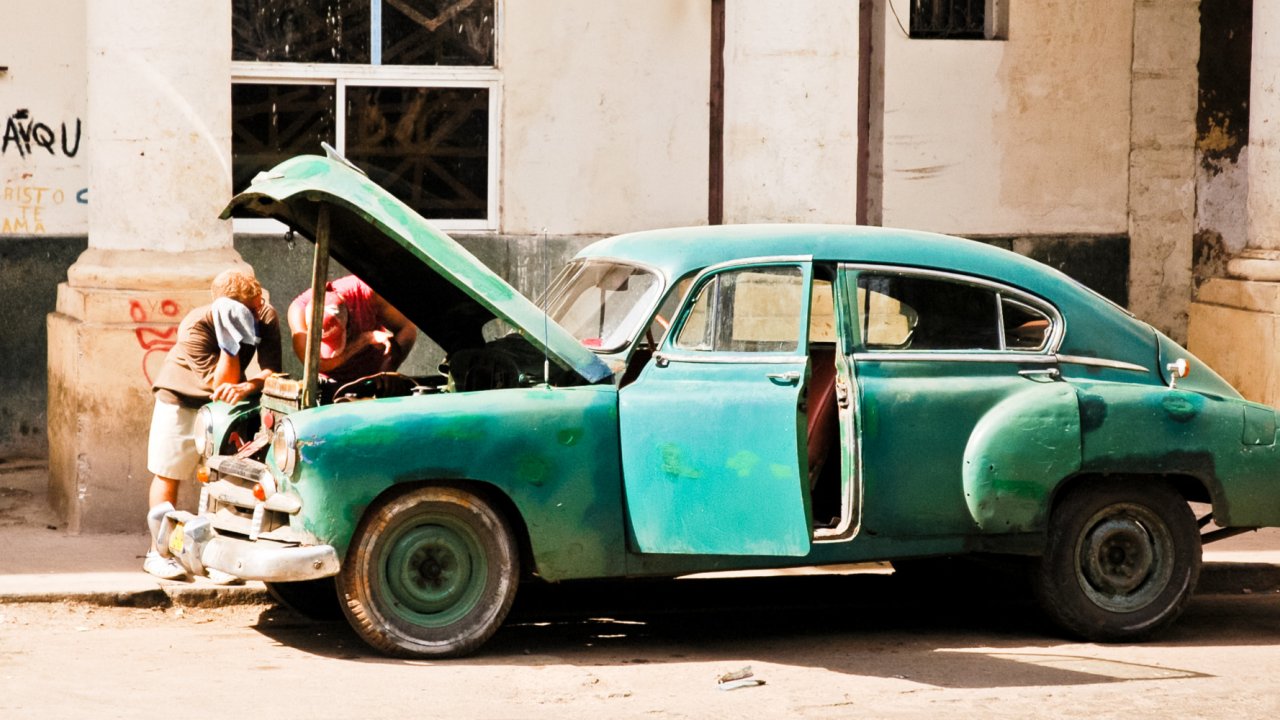 A classic old blue Cuban car with the hood open as someone works on the car on a sunny day in Eastern Cuba