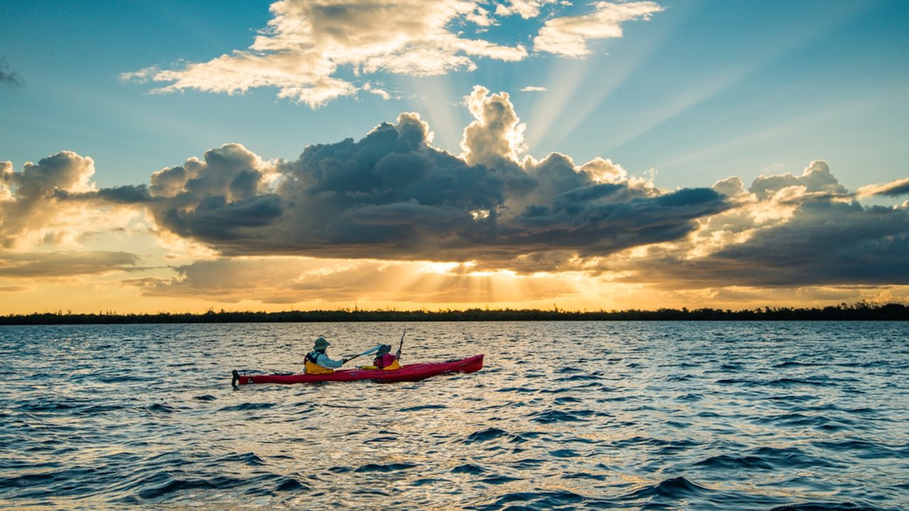 A group of sea kayakers paddling at sunset in the waters outside of Havana, Cuba.