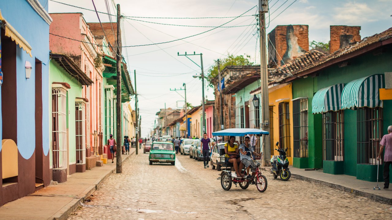 Old street with people walking on the sidewalk in Cuba