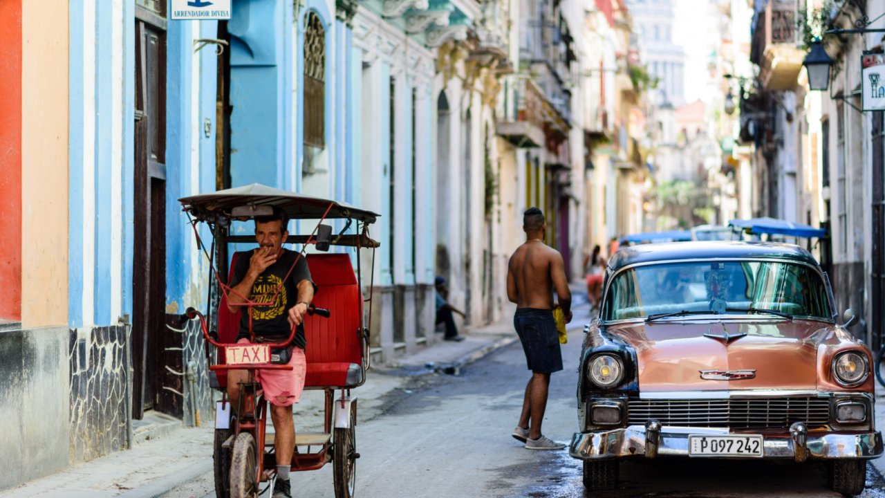 Colorful street with an old red car on the left side in Havana Cuba