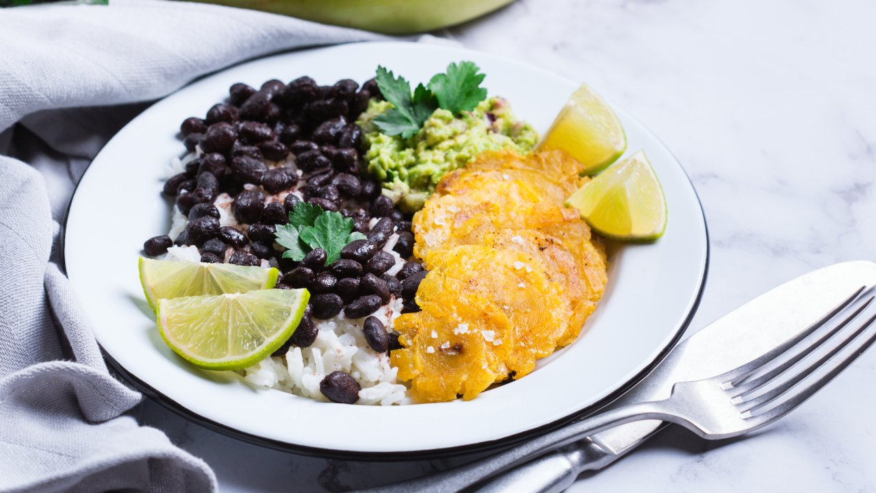 A plate of traditional Caribbean food with black beans, white rice, and plantains