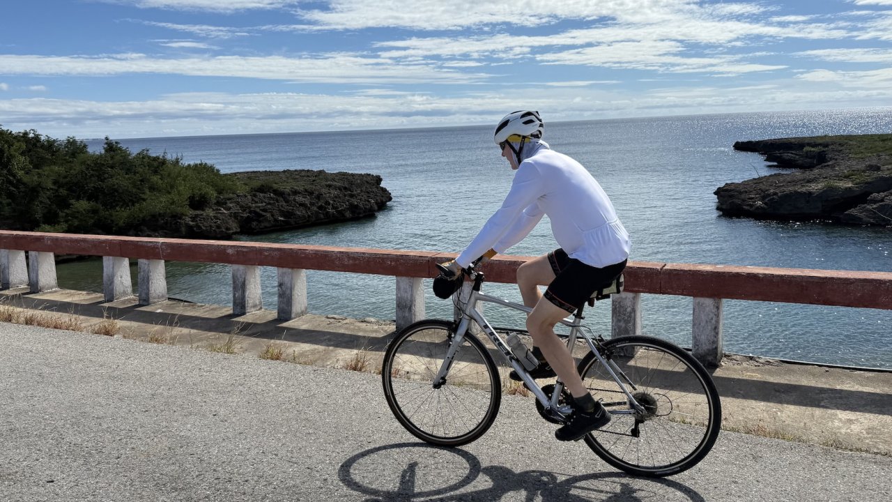 Cyclist riding along Cuba’s scenic coastline on a bike tour, showcasing the relaxed pace and beauty of Cuba travel by bicycle