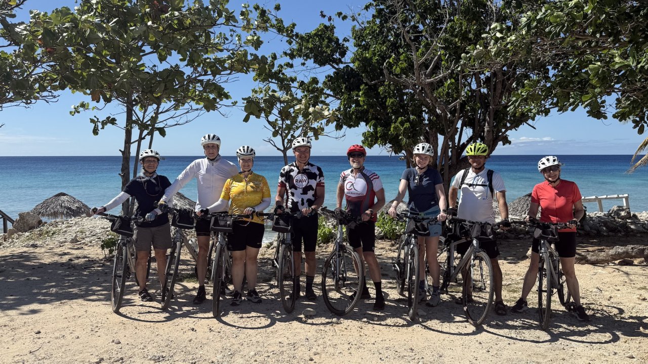 Travelers posing with bicycles on a beach during a Cuba bike tour, blending outdoor adventure with cultural Cuba tours