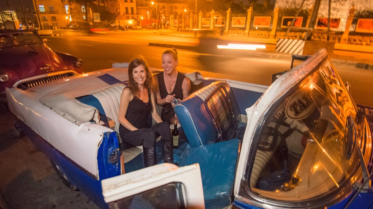 Two women in a classic american convertible in Cuba on a cuba travel tour.