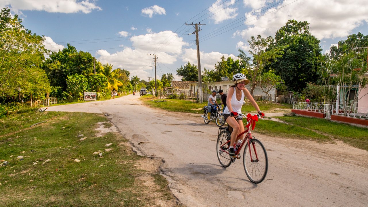 A person on a bike on a paved road in Cuba on a sunny day