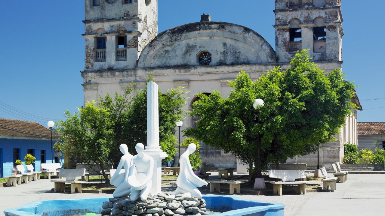 Historic church and public square in Eastern Cuba under bright blue skies, showcasing local architecture and small-town charm.