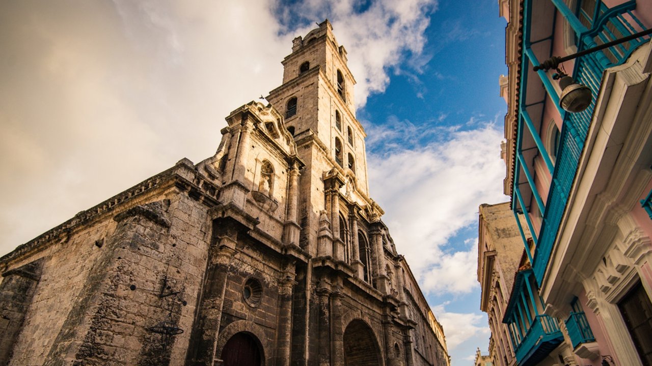 Historic stone church and colorful colonial buildings in Old Havana, Cuba, showcasing the city’s classic architecture.