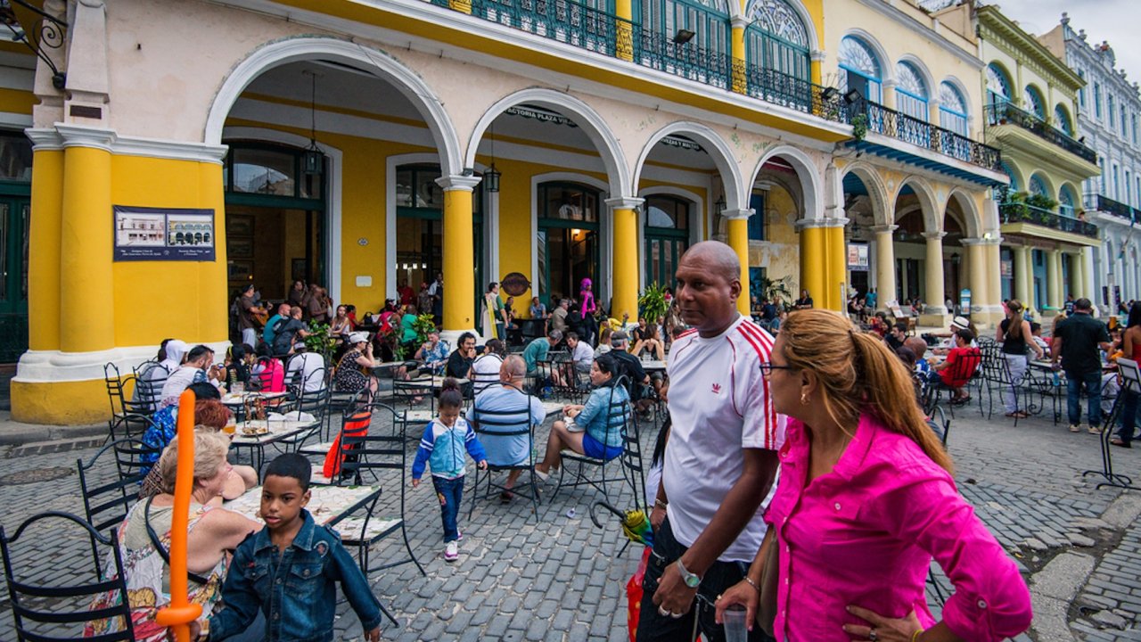 Locals and visitors enjoying drinks and conversation at a vibrant café in Havana during a guided day tour.