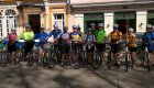 A group of people standing next to their bikes smiling in front of colorful homes on a group bike tour in Cuba