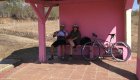 Two tourists and a bike sitting at a pink rest stop 