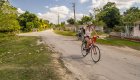 A woman smiling while riding her bike on a paved road in Cuba