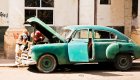 A classic old blue Cuban car with the hood open as someone works on the car on a sunny day in Eastern Cuba