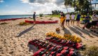Life jackets and sea kayaks scattered across the beach with people lined up to get gear