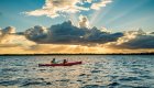 A group of sea kayakers paddling at sunset in the waters outside of Havana, Cuba.