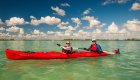 Two people in a sea kayak in Cuba paddling over the clear water.