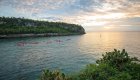 Panoramic view of a channel in the Caribbean with a numerous red sea kayaks paddling out into the sunset