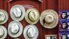 A series of sun hats hung on a door next to a row of stickers of the Cuban flag
