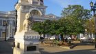 A building in Cuba with a lion statue in front of it and a nice park around.