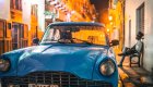 classic blue car on a busy street at night in Cuba