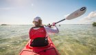 A woman sea kayaking through clear water on a sunny day in Cuba.