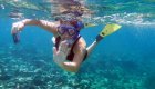 Traveler snorkeling over a vibrant coral reef in Cuba’s clear Caribbean waters, waving toward the camera.